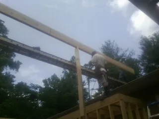 Carpenter setting a ridge beam over a new addition frame — Ice Dam Removal by Roofing Brothers in Rocky Point
