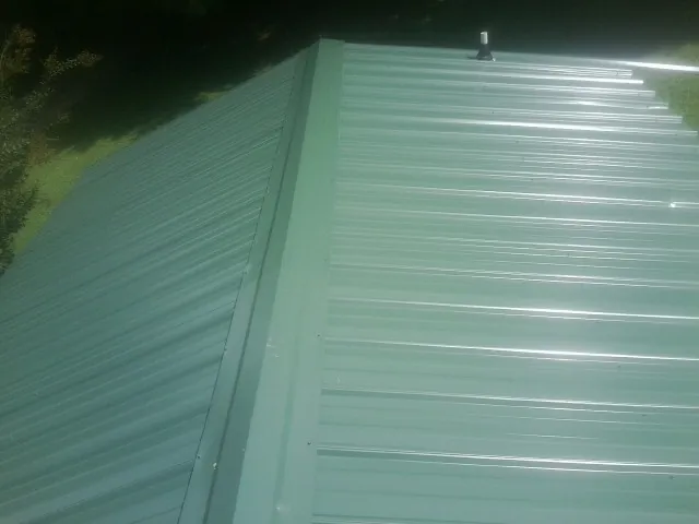 New green metal panels meeting at the ridge of a roof — Flat Roof Repair work by our crew in Rocky Point