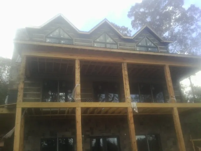 Dormers and porch framing on a large log home under construction — Roof Coating work by our crew in Rocky Point