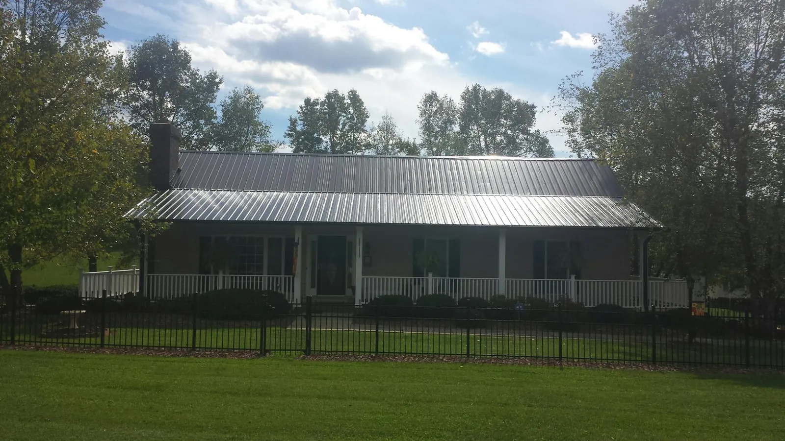 Gray metal roof on a brick ranch with a full width front porch — Gutter Guard Installation work by our crew in Rocky Point